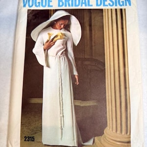 May include: A Vogue Bridal Design sewing pattern envelope, number 2315, featuring a white long-sleeved gown with a matching hooded cape and a braided waist tie. The illustration shows the garment worn with yellow calla lilies in hand.