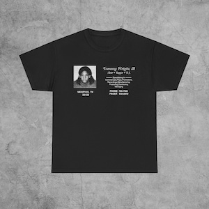 May include: Black t-shirt with a white graphic of a man's headshot and text that reads "Tommy Wright, III Actor Rapper DJ. Specializing in Commercials Plays Promotions Recordings, Manufacturing Producing Distributing Managing PHONE 789-7961 PAGER 532-2672 MEMPHIS, TN 38109"