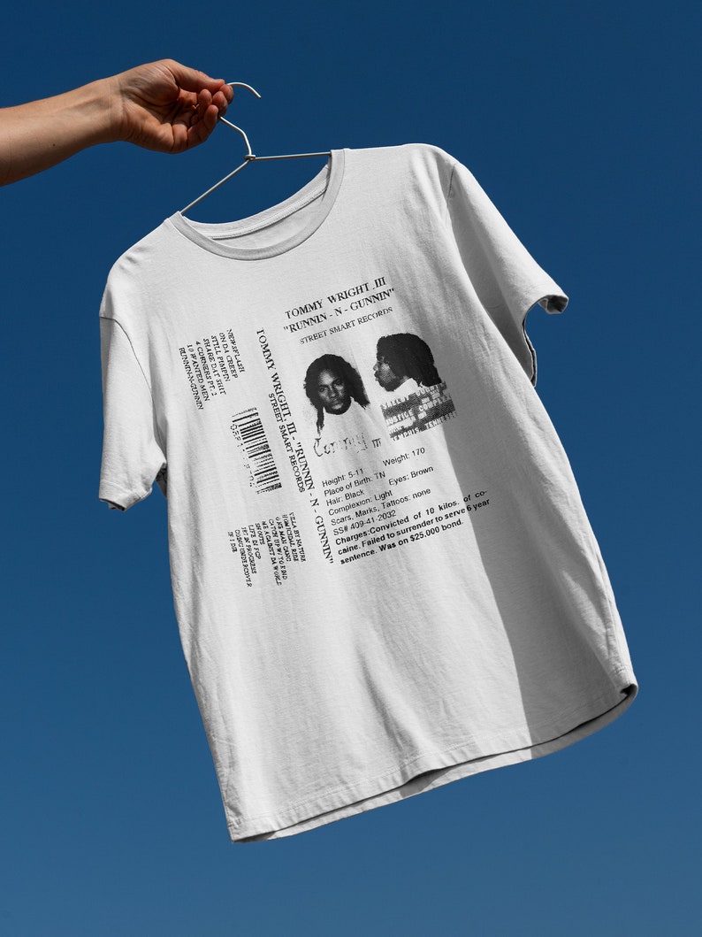 May include: White t-shirt with a black and white image of a mugshot. The mugshot is for Tommy Wright III, and the text "Runnin-N-Gunnin" is printed above the image. The text "Street Smart Records" is printed below the image.