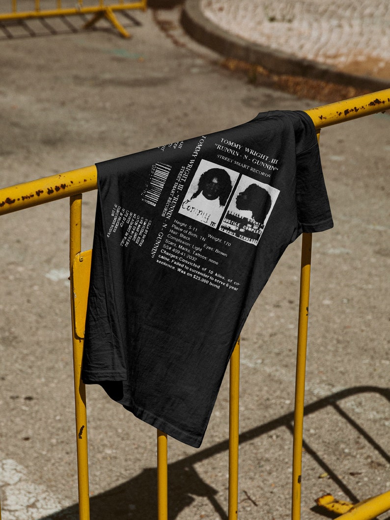 May include: Black t-shirt with a white graphic of a mugshot featuring the text "Tommy Wright III - "Runnin-N-Gunnin" Street Smart Records".