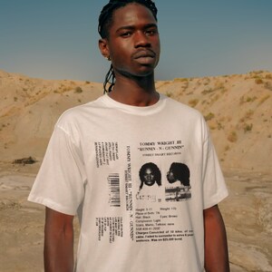 May include: White t-shirt with a black and white image of a mugshot on the back. The mugshot is labeled "Tommy Wright III - "Runnin-N-Gunnin" Street Smart Records". The text below the mugshot includes details like height, weight, place of birth, hair color, complexion, eyes, scars, marks, tattoos, social security number, charges, and sentence.