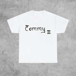 May include: White t-shirt with black text that says "Commy III" on the front.