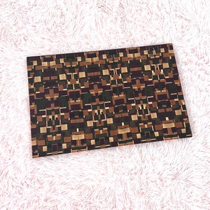 May include: A brown and green chopping board with a geometric pattern. The board is made of wood and has a rectangular shape.