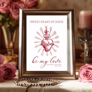 May include: Framed print with the text "Sweet Heart of Jesus" and "be my love" in red script. The image features a heart with a crown and rays, set against a backdrop of pink roses, candles, and a crucifix. A rosary is in the foreground.