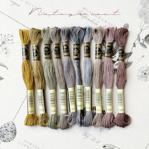 Może przedstawiać: Zestaw 10 szpulek nici do haftu w różnych odcieniach brązu, zieleni i szarości. Szpulki są oznaczone numerami, a nazwa marki "Meadowsweet" jest widoczna w górnej części obrazu.