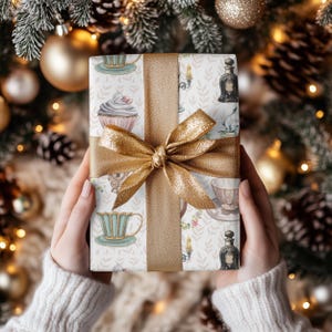 wrapping paper with whimsical vintage tea party illustrations including teacups, cupcakes, candlesticks, keys, and perfume bottles in pastel tones