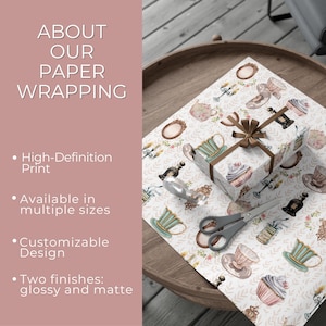Puede incluir: Una caja de regalo envuelta en papel estampado con tazas de t&eacute;, pasteles y dise&ntilde;os florales. El papel est&aacute; sobre una mesa de madera con tijeras y una botella decorativa. El texto a la izquierda dice "About Our Paper Wrapping".