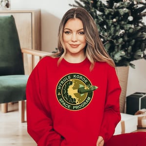 a woman wearing a red sweatshirt with a green logo