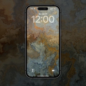 Puede incluir: Un smartphone con un diseño de fondo de pantalla veteado en tonos marrón, dorado y azul. La pantalla muestra la hora 12:00 y la fecha Sáb 31 Ene. El teléfono tiene un marco negro y el logotipo de AT&T es visible.