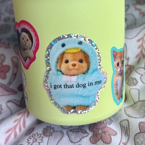 May include: A light green reusable water bottle with a variety of colorful stickers. The stickers feature cartoon animals and the text "i got that dog in me".
