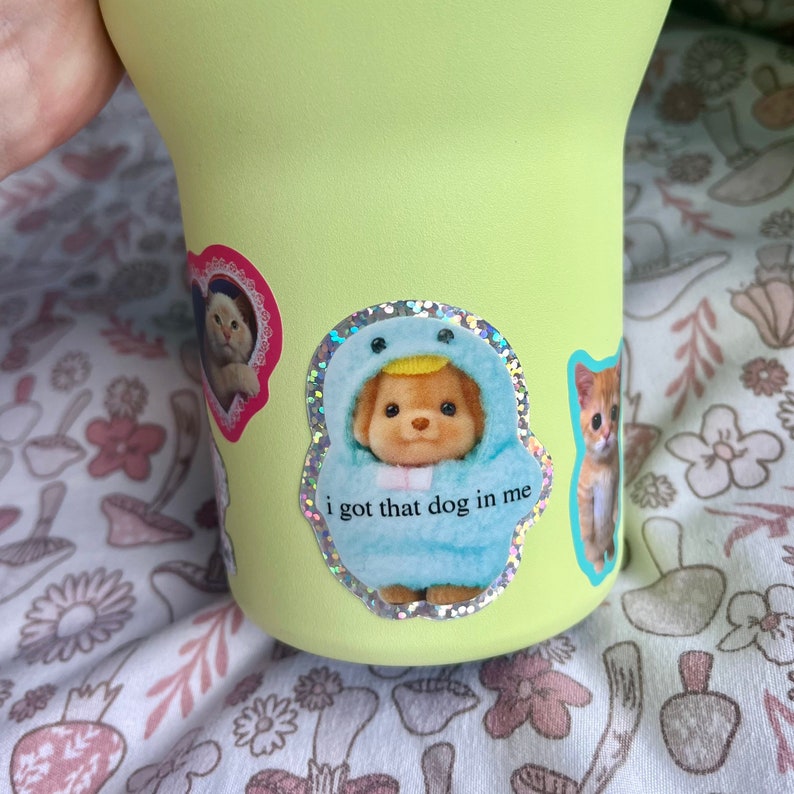 May include: A light green reusable water bottle with a variety of colorful stickers. The stickers feature cartoon animals and the text "i got that dog in me".