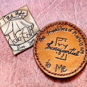 May include: A brown leather keychain with the text "The trivialities of Mortals are In consequential to Me" in a cursive font.