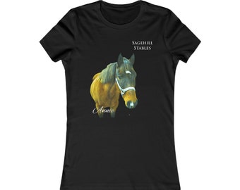 Puede incluir: Camiseta negra para mujer con una ilustración de un caballo marrón y negro. El caballo lleva una cabezada blanca y el texto "Sagehill Stables" y "Annie" están impresos en la camiseta.