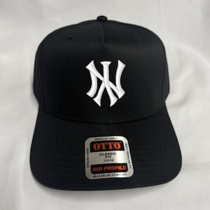 May include: Black baseball cap featuring a white NY logo. The cap has a curved peak and a structured fit. The label on the brim reads "OTTO CLASSIC FIT OSFM MID PROFILE MAXIMUM COMFORT".