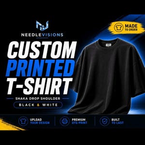 May include: Black custom printed t-shirt with a drop shoulder design. The shirt is made to order and features the text "Custom Printed T-Shirt" in white and blue. The brand name "Needle Visions" is at the top. The shirt is black and white.