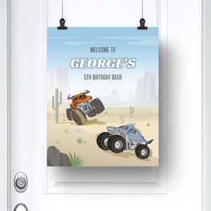 May include: A blue and white birthday party sign with the text "Welcome to George's 5th Birthday Bash". The sign features two cartoon monster trucks in a desert landscape.