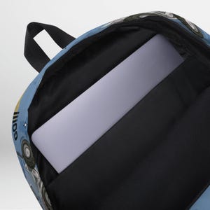 May include: A blue and white backpack with a laptop compartment. The backpack has a graphic of a cartoon character with the word "Go!" on it.