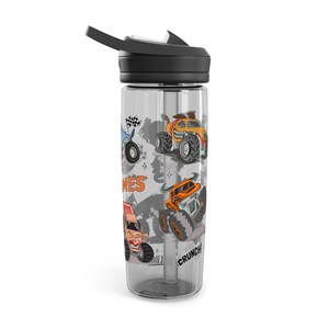 May include: Clear water bottle with a black lid and a flip-top spout. The bottle features colorful illustrations of monster trucks in orange, yellow, and blue. The text "CRUNCH!" and "MES" are also visible on the bottle.