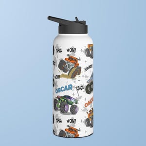 May include: White stainless steel water bottle with a black lid and a colourful monster truck design. The bottle has the words "WOW!" and "GO!!!" printed on it. The name "OSCAR" is printed on the bottle twice.