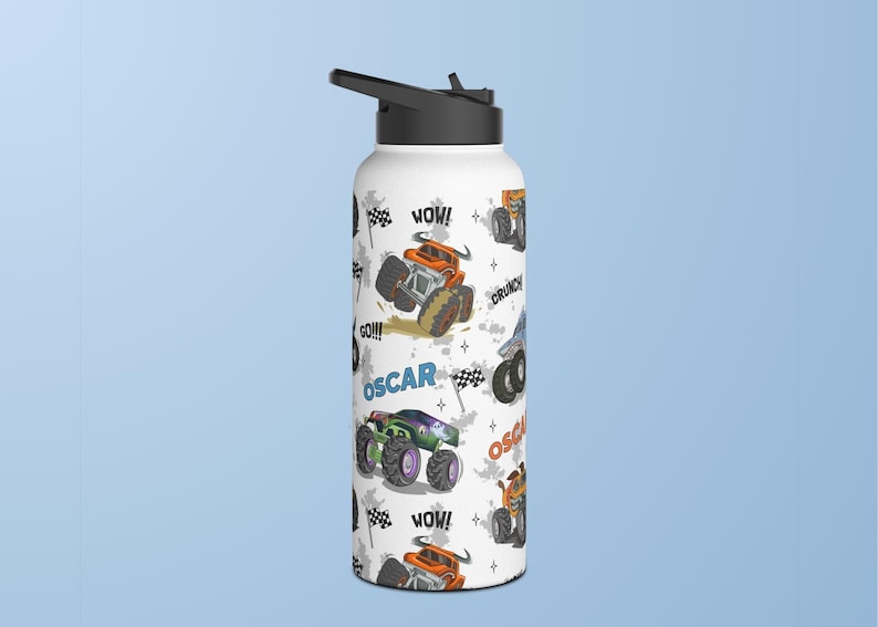 May include: White stainless steel water bottle with a black lid and a colourful monster truck design. The bottle has the words "WOW!" and "GO!!!" printed on it. The name "OSCAR" is printed on the bottle twice.