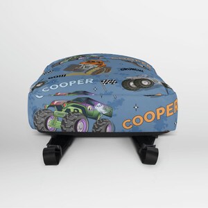 May include: Blue backpack with a repeating pattern of monster trucks, stars, and the word "COOPER".