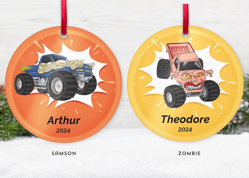 May include: Two round Christmas ornaments with red ribbon hangers. One is orange with a blue monster truck and the name "Arthur" and the year "2024". The other is yellow with a pink monster truck and the name "Theodore" and the year "2024".