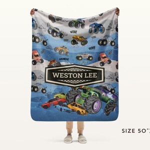 May include: A personalized blanket featuring a colorful monster truck design. The blanket has a blue and white background with various monster trucks and the name "WESTON LEE" in a black and white banner. The blanket measures 50" x 60".