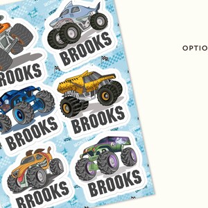 May include: A sheet of stickers featuring colorful monster trucks with large tires. Each truck has a unique design, including a shark, a bull, and a grinning face. The name "BROOKS" is printed below each truck.