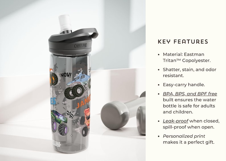 May include: A clear water bottle with a black lid and a gray handle. The bottle is decorated with colorful monster truck graphics and the name "JAMES". The bottle is made of Eastman Tritan Copolyester.