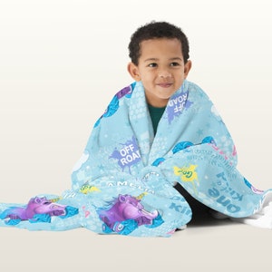 May include: A blue fleece blanket with a unicorn and off-road vehicle print. The blanket features the text "Off Road", "Go", "Kill 'em all", "One of a Kind", and "A Million Miles".
