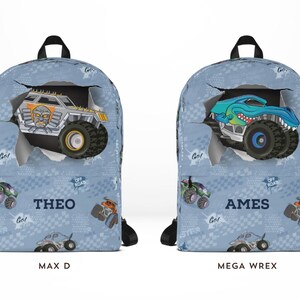 May include: Two blue backpacks with monster truck designs. One features a silver truck with the name "THEO" and the other a blue truck with the name "AMES". Both have black straps and handles, with "MAX D" and "MEGA WREX" printed below.