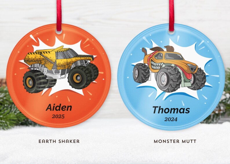 May include: Two round Christmas ornaments with red ribbons. One is orange with a yellow monster truck and the name "Aiden" and the year "2025". The other is blue with a monster truck and the name "Thomas" and the year "2024".