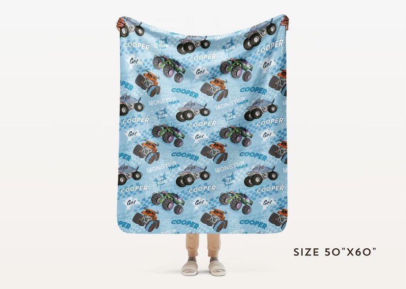 Pu&ograve; includere: Una coperta in pile blu e bianca con un motivo ripetitivo di monster truck. I camion sono blu, neri e arancioni con la scritta "COOPER" stampata su di essi. La coperta misura 127 cm per 152 cm.
