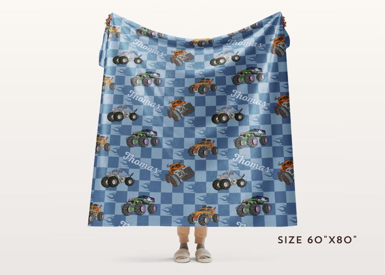 May include: A blue and white checkered fleece blanket with a repeating pattern of monster trucks and the name "Thomas". The blanket is 60 inches by 80 inches.
