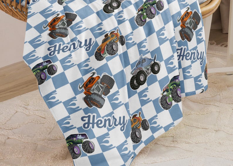 May include: A blue and white checkered baby blanket with a monster truck design and the name "Henry" repeated throughout.