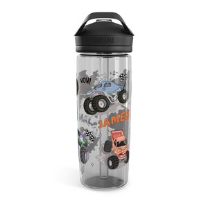 May include: Clear water bottle with a black lid and handle. The bottle features colorful monster truck graphics, including a shark-themed truck and the name "JAMES". The word "WOW!" is also displayed.