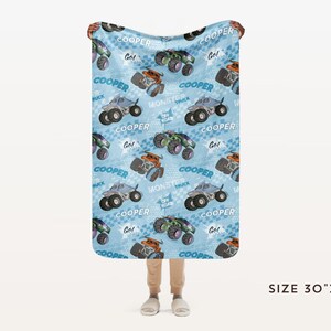 Pu&ograve; includere: Una coperta in pile blu e bianca con un motivo ripetitivo di monster truck. I camion sono blu e grigi con ruote nere e le parole "COOPER" e "Monster Truck" sono stampate sulla coperta. La coperta misura 76 cm per 102 cm.