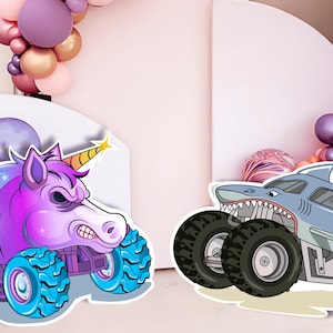 Op de afbeelding: Een paarse eenhoorn monstertruck met blauwe wielen en een gele hoorn, en een blauwe haai monstertruck met zwarte wielen. Beide trucks zijn in cartoon-stijl en hebben een witte achtergrond.