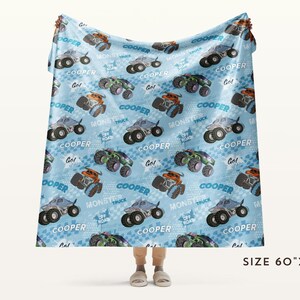 Pu&ograve; includere: Una coperta in pile blu e bianca con un motivo ripetitivo di monster truck. I camion sono verdi, neri e arancioni con il nome "Cooper" stampato su ogni camion. La coperta misura 152 cm per 203 cm.