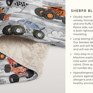May include: Sherpa blanket with a repeating pattern of monster trucks in orange, blue, and red on a grey background. The blanket has a soft, plush, cream-coloured underside.