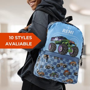 May include: A light blue backpack featuring a monster truck design with green and purple accents. The backpack has a checkered pattern on the bottom and the name "REMI" on top. The text "10 STYLES AVAILABLE" is also visible.