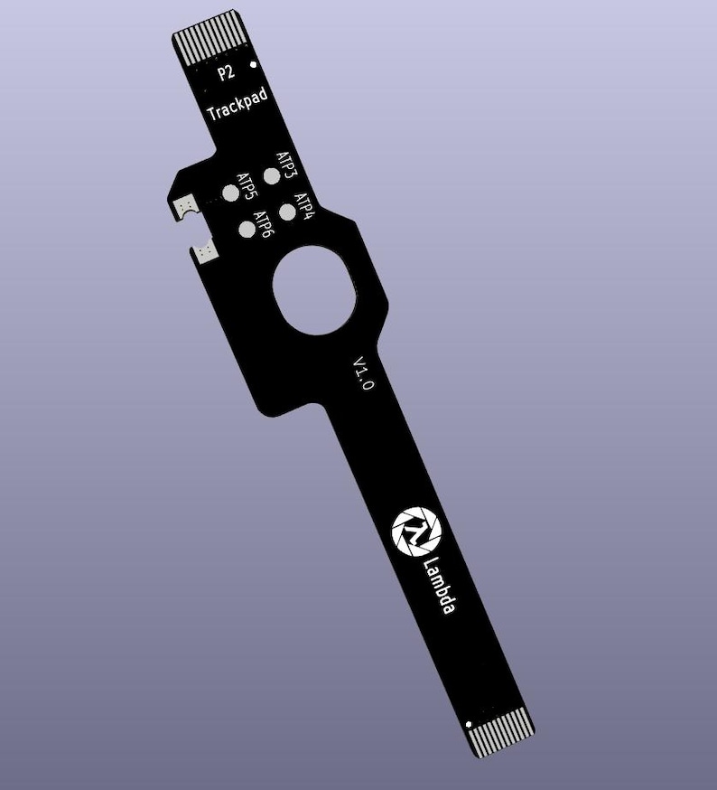 Op de afbeelding: Zwart printplaat met de tekst "P2 Trackpad", "ATP3 ATP4", "ATP5 ATP6", "V1.0" en het Lambda-logo. De printplaat heeft een unieke vorm met een gat en meerdere aansluitpunten.
