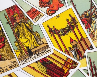 May include: A collection of tarot cards featuring colorful illustrations and text. The cards depict various figures, including a queen, knights, and other symbolic imagery. The cards are arranged in a scattered pattern, with the "Queen of Wands" card prominently displayed.