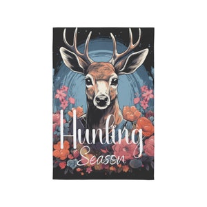 May include: A stylized illustration of a deer's head with antlers, surrounded by colorful flowers. The text "Hunting Season" is written in white script below the deer.