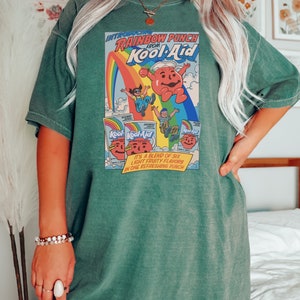 a woman standing in front of a bed wearing a green shirt