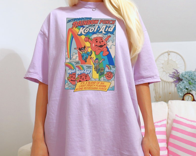 a blonde haired woman wearing a purple cartoon t - shirt