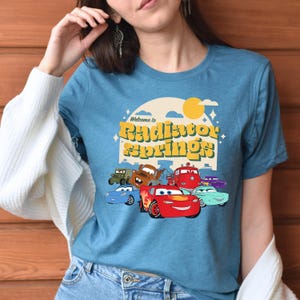 a woman wearing a blue shirt with cars on it