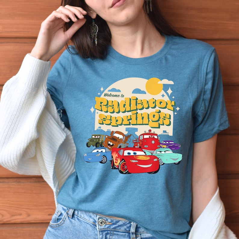 a woman wearing a blue shirt with cars on it