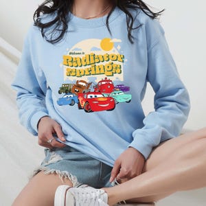 a woman wearing a blue sweatshirt with cars on it