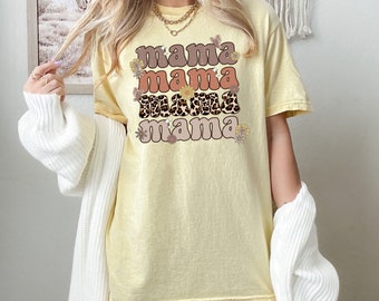 May include: A yellow t-shirt with the text "mama mama mama mama" in a retro font with floral accents.